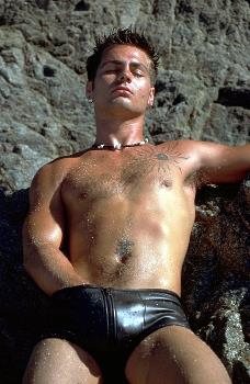 Sexy spunk of a guy at the beach wearing leather shorts with a zipper.